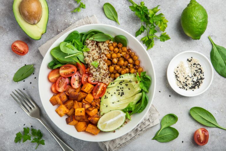 Vegane Bowl mit Avocado, Quinoa, Süßkartoffel, Tomaten, Kichererbsen, Limetten und Spinat